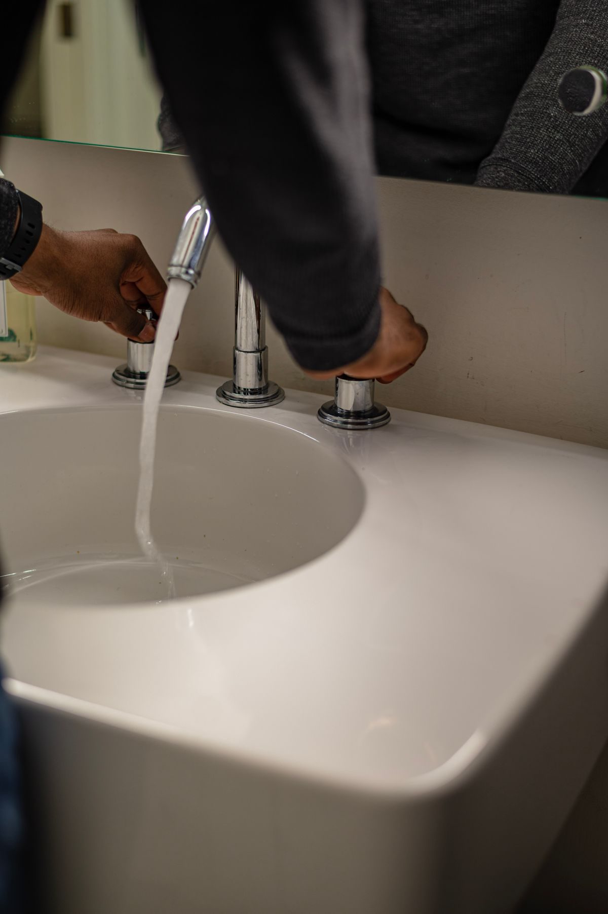 Hands testing water flow at a modern bathroom faucet