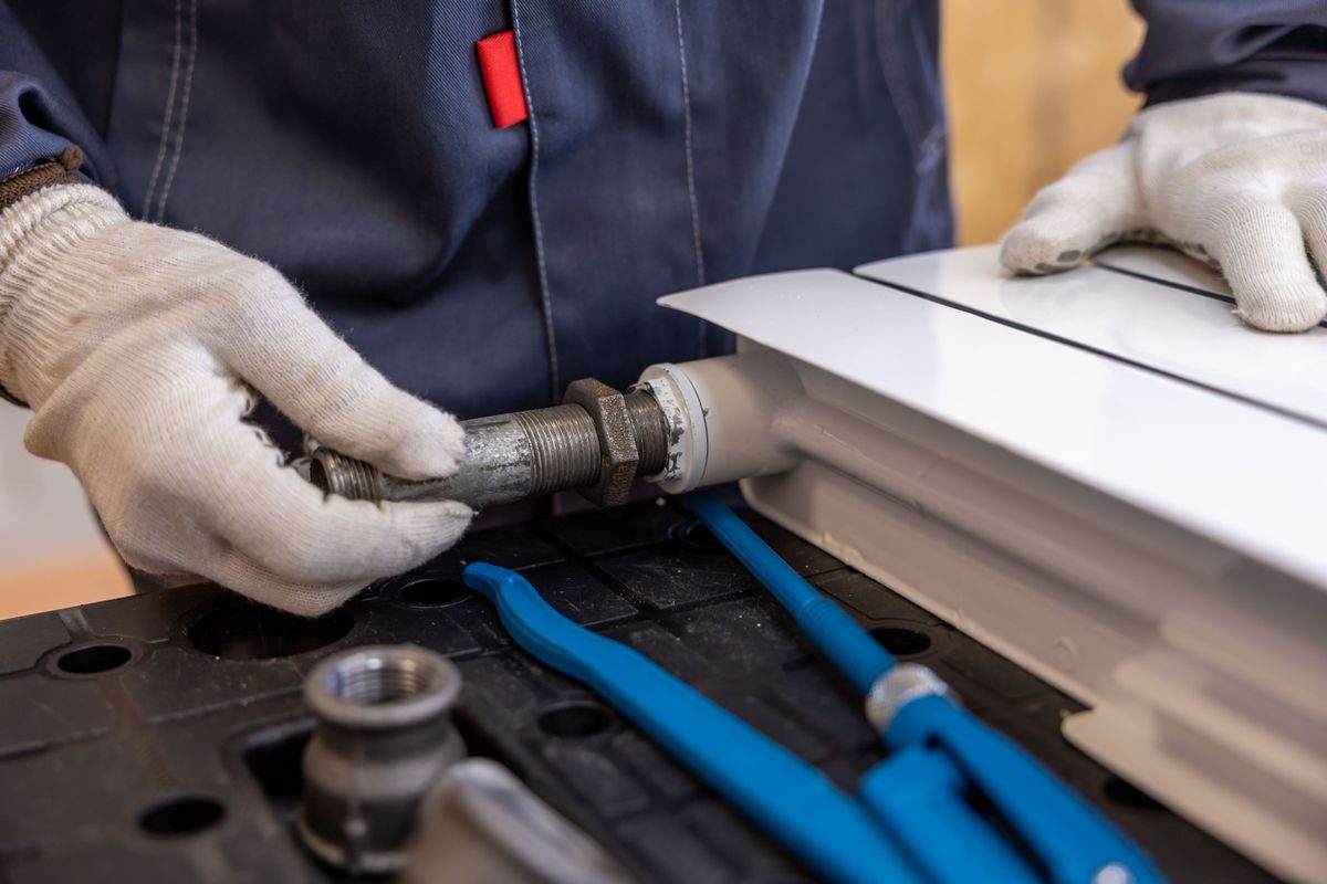 Plumber installing a gas radiator pipe with professional tools
