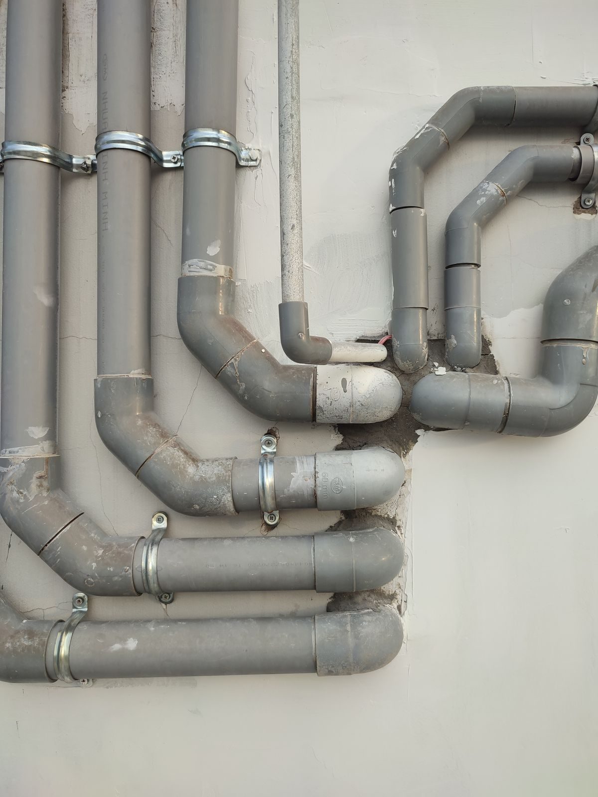 Gray PVC sewer pipes mounted on an exterior wall